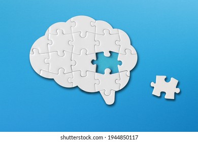 Brain shaped white jigsaw puzzle on blue background, a missing piece of the brain puzzle, mental health and problems with memory	