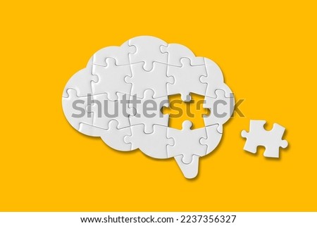 Brain shaped white jigsaw puzzle on yellow background, a missing piece of the brain puzzle, mental health and problems with memory