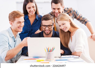 Brainstorm. Group Of Cheerful Business People In Smart Casual Wear Looking At The Laptop Together And Smiling 