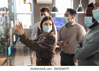 Brainstorm, Presentation And Teamwork Concept. Creative Focus Group Of Diverse Professional Businesspeople In Face Masks Thinking, Looking At Sticky Post-it Notes On Glass Wall Discussing New Ideas