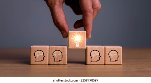 brainstorming creative idea and innovation. Hand putting over wooden cube block with light bulb icon on many people together having an idea symbolized by icons on cubes. - Shutterstock ID 2259798597