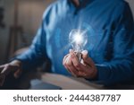 brainstorming, future, genius, imagination, intelligence, invention, leadership, learning, plan, strategy. A man is holding a light bulb. The light bulb is surrounded, giving it a futuristic.