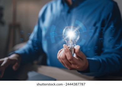 brainstorming, future, genius, imagination, intelligence, invention, leadership, learning, plan, strategy. A man is holding a light bulb. The light bulb is surrounded, giving it a futuristic.
