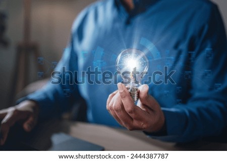 brainstorming, future, genius, imagination, intelligence, invention, leadership, learning, plan, strategy. A man is holding a light bulb. The light bulb is surrounded, giving it a futuristic.