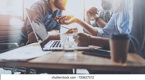 Brainstorming Process At Sunny Office.Young Coworkers Work Together Modern Office Studio.Young People Making Conversation At Wooden Table.Horizontal Wide.Blurred Background