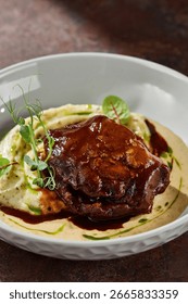 Braised beef cheek with mashed potatoes in demi-glace, moody lighting, overhead composition.