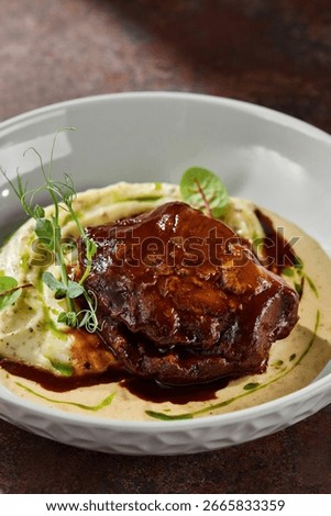 Braised beef cheek with mashed potatoes in demi-glace, moody lighting, overhead composition.