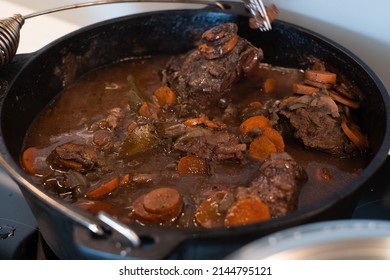 Braised Beef Cheeks Cooking In Red Wine Sauce In Cast Iron Dutch Oven. Slow Cooked Meat Stew.