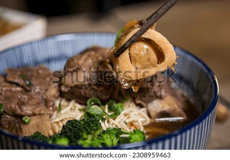 Braised beef noodle soup with chopsticks close-up.