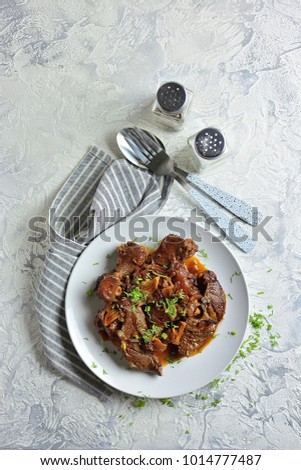 Braised mutton in a plate, top view, meat stag, light gray textured background, copy space