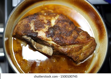 Braised Pork Roast Cooked In A Dutch Oven Resting On The Stove Top.