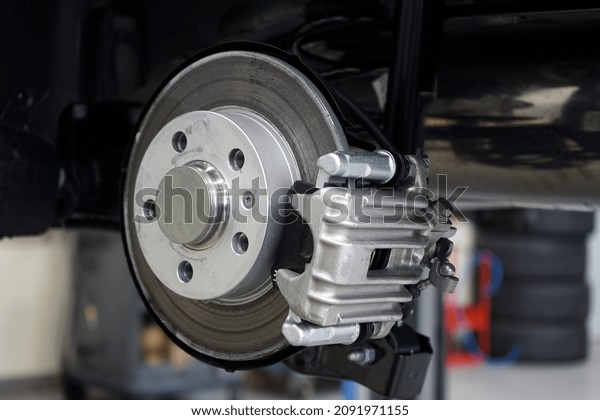 Brake disc and brake caliper\
installed on a modern car. Selected focus. The background is\
blurred.