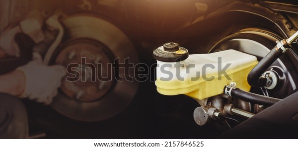 Brake fluid\
reservoir of car brake system with a disc brake repairing double\
exposure blurred on\
background