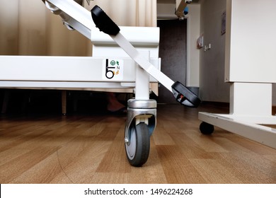 Brake Pedal At The Foot Of A Patient Hospital Bed With Illustrated Operation Instruction Where The Lock Mechanism Can Be Engaged By Pressing On The Lever So That The Bed Does Not Roll Or Move.