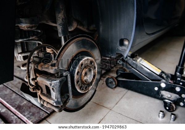 Braking system car, with brake disc\
and brake pad. Repairing suspension of automobile at\
garage.