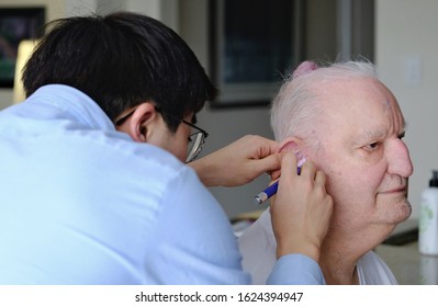 BRAMPTON, ONTARIO/CANADA - SEPTEMBER 23 2020: Doctor Or Technician Removing Wax From Ear Of Senior Male