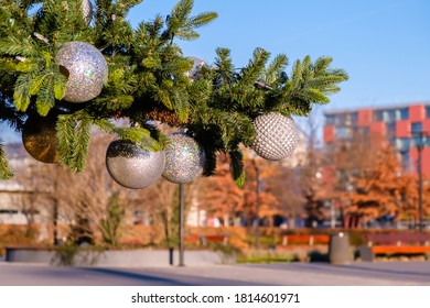 Branch Of Artificial Christmas Tree With White Christmas Balls On Empty City Street Outdoors At Sunny Summer Day. No Snow, No People.