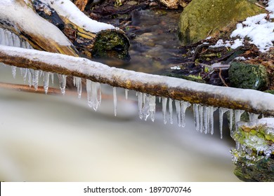 Branch covered in ice over fast flowing river water