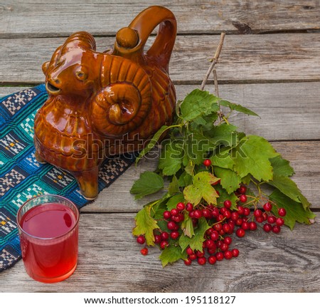 A branch of viburnum on the background of traditional Ukrainian vessel "Kumanez" on a wooden table. Products of mass production in the  national traditions
