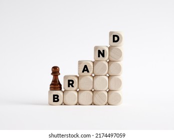 Brand building or development concept. Pawn chess piece is climbing the ladder of wooden cubes with the word brand.