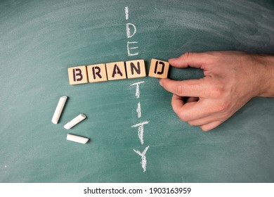 Brand and Identity concept. Text from letters of the wooden alphabet on a green chalk board - Shutterstock ID 1903163959