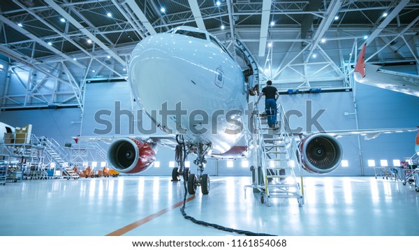 航空機整備用の格納庫に立つ新しい飛行機 航空機整備士 技術者 整備士がはしご スロープを経てキャビンに入る の写真素材 今すぐ編集