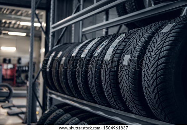 Brand new big variety of car\'s tyres on shelf\
with prices at store or\
warehouse.