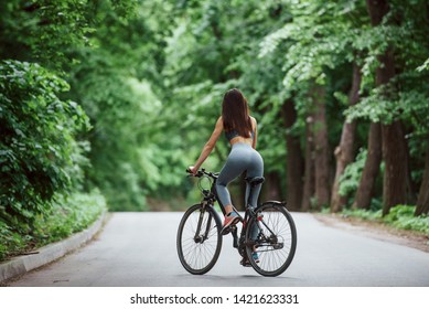 Brand New Bike. Female Cyclist On Asphalt Road In The Forest At Daytime.