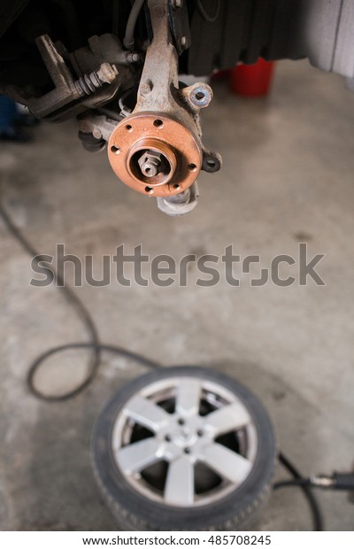 Brand new brake disc on car in a garage. Auto mechanic\
repairing .