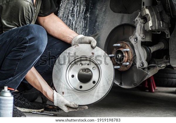 Brand\
new brake discs for garage cars. Auto mechanic,in process of new\
tire replacement, Car brake repairing in\
garage	