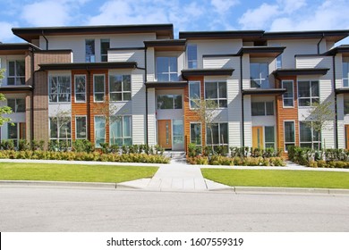 Brand new Contemporary townhomes in the suburbs of Surrey, B.C. Canada. Facade of attached homes with a sidewalk leading to small front yard. 
