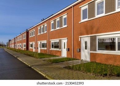 Brand new development of basic public housing in a village in the Netherlands. Neighborhood scene of street with modern suburban terraced houses.