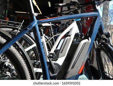 Brand New Electric Bicycles Or E Bike, With Their Batteries In The Foreground, In A Shop Window.