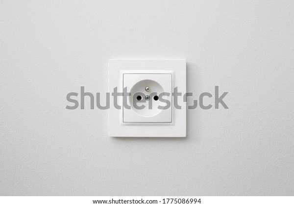 Brand new electrical socket isolated on\
gray wall. Renovated studio apartment power supply background.\
Empty copy space white plastic power\
outlet.