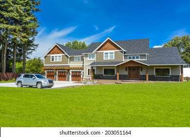 Brand New Farmer's House With Car Parked On Driveway In Front. Huge Family House With Three Garage Door And Blue Sky Background. British Columbia, Canada. 