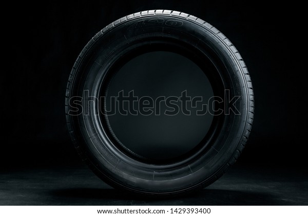 Brand new modern car tyre on a black background.\
Studio shot