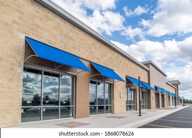 Brand New No Logo, Signage Or Label Storefront Of A Under Construction Strip Mall In The USA With Blue Awnings Above The Entrance, Blue Cloudy Sky Reflecting On The Windows