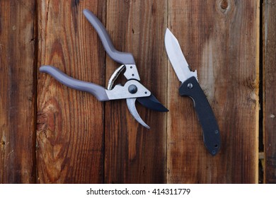 Brand New Pruning Shear And A Folder Knife On The Wooden Table