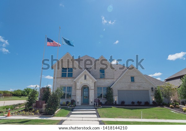 Brand new two story house with attached garage in\
new development neighborhood near Dallas, Texas, USA. Model house\
with American flag