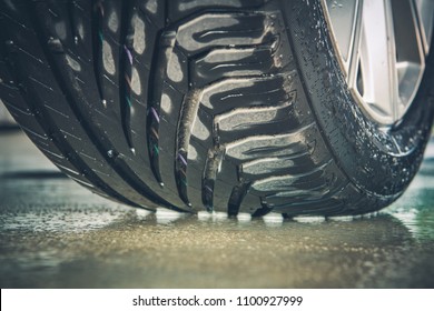 Brand New Vehicle Tire Tread Closeup Photo. Car Wheel On The Wet Pavement.