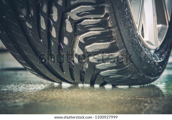 Brand New Vehicle Tire Tread Closeup Photo. Car\
Wheel on the Wet\
Pavement.
