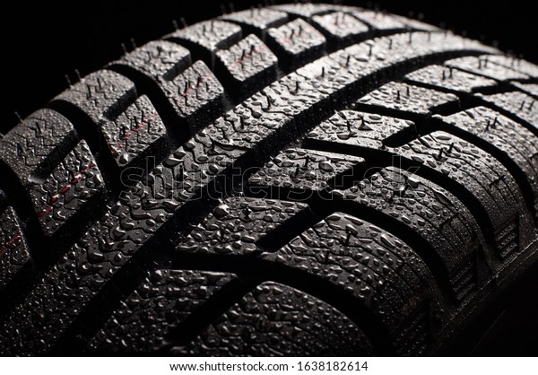 Brand new
winter tire pattern on black
background.