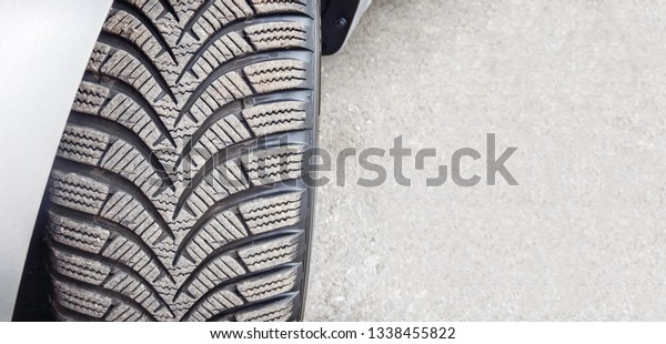 Brand new winter tires with\
modern tread just mounted on car wheel - Concept of safe driving\
with new car tire - Automobile tire first road roll out copy\
space