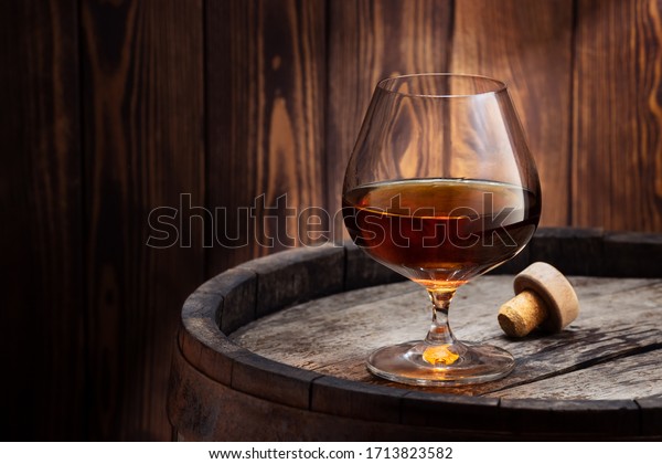 brandy or cognac in snifter glass on old wooden\
barrel as table
