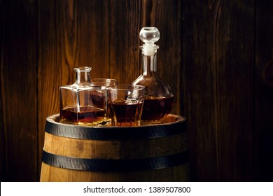 brandy and brandy in decanters stand on an oak barrel, strong alcoholic drinks in the basement