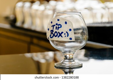 A brandy glass "Tip Box" on the counter of a bar.