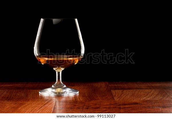 Brandy snifter on a bar top isolated on a\
black background