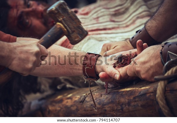 Brasov, Romania - April 14, 2017: Actor playing Jesus Christ is getting his hands nailed while being crucified during the reenactment of the Way of the Cross on Good Friday.