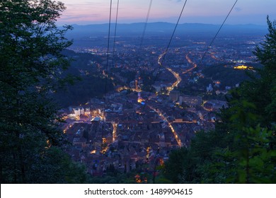 Brasov Seen From The Tracking Road To Tampa Peak. Lights Over The City And Council Square Can Be Seen In The Close Distance And The Mountains At The Horizon