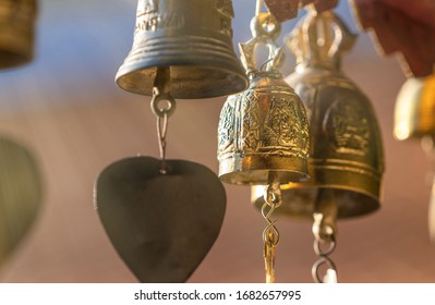 ฺSmall Brass Bells Hanging On Temple Roof, Close Up Shinning Beautiful Brass Bells. Faith Of Buddhism In Thailand. Soft Warm Light Beam In The Air. Selected Focus, Blur Background And Foreground.